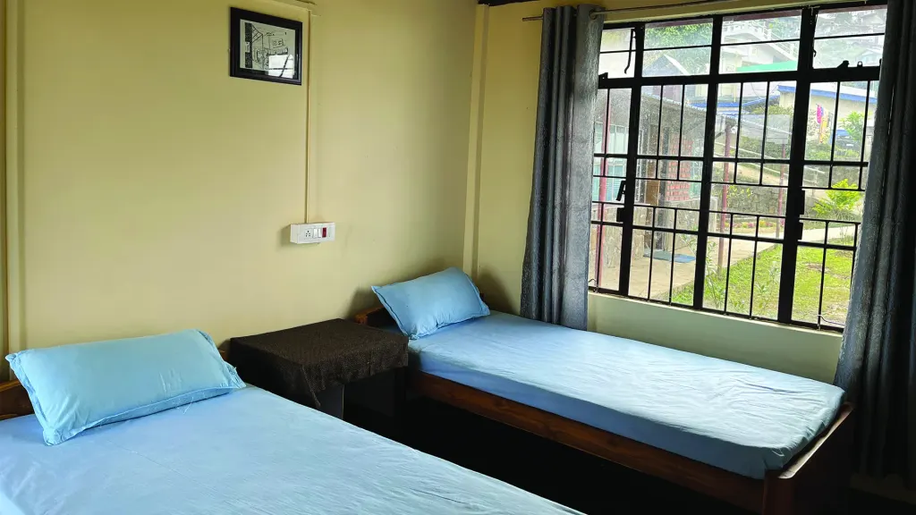 Room 4 with beds under a large window looking onto greenery