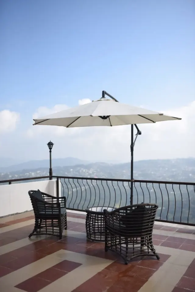 Balcony seating under a white umbrella with a view of the hills