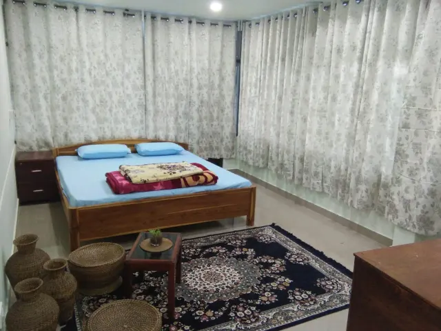 A bedroom with a patterned rug and floral curtains