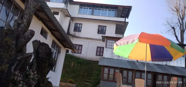 Uvie Homestay building beside an old tree, with a garden umbrella in front