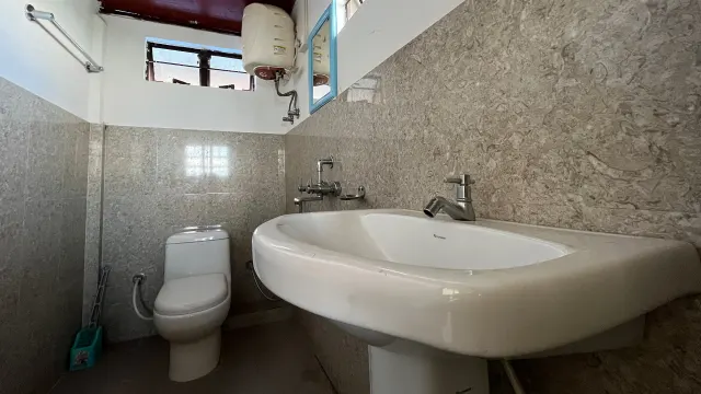 Attached bathroom of Room 1 with a wash basin and western toilet